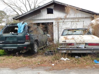 Junk cars in front of garage
